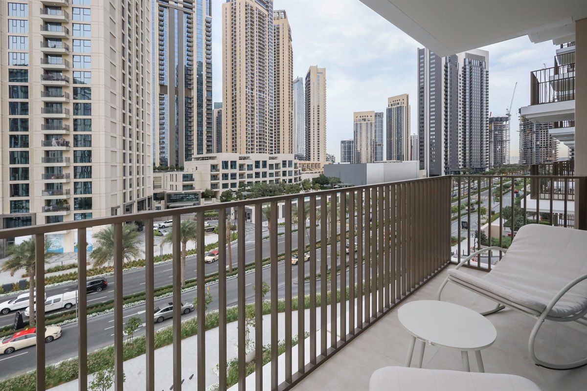 A balcony with a view of a cityscape, including tall buildings and a road with cars.