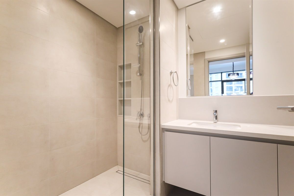 Une salle de bain moderne avec une douche à parois de verre, un lavabo blanc et un grand miroir.