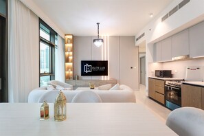 A modern hotel room with a sofa, dining table, and kitchen area.