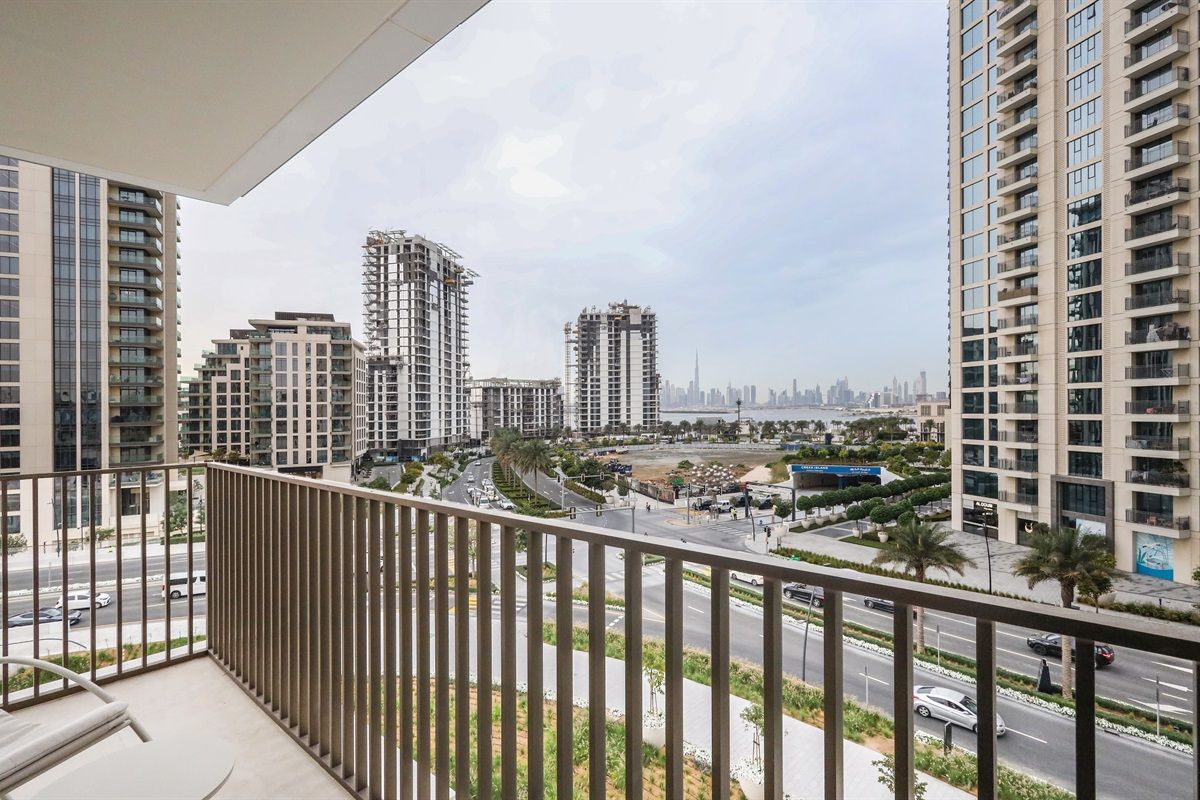 A balcony with a view of a cityscape, including high-rise buildings and a road.