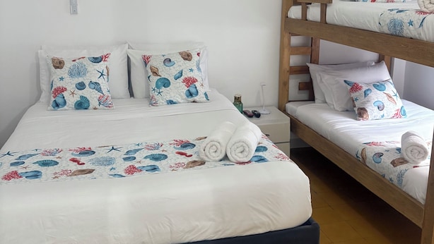 A room with a bunk bed, a single bed with patterned pillows, and an air conditioning unit on the wall. - Turbay House 1 (Cartagena de Indias)