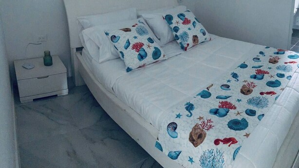 A bedroom with a bed, two pillows, a bedside table, and a nightstand. - Casa Turbay 11 (Cartagena de Indias)