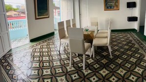 A room with a patterned floor, white walls, a framed picture, and a TV on the wall. - Turbay House 13 (Cartagena de Indias)