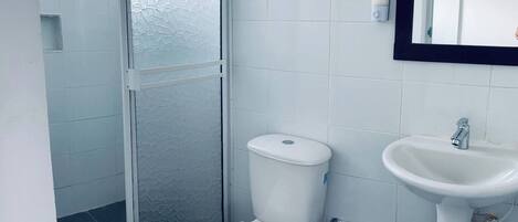 A bathroom with a toilet, a sink, and a glass shower enclosure.
