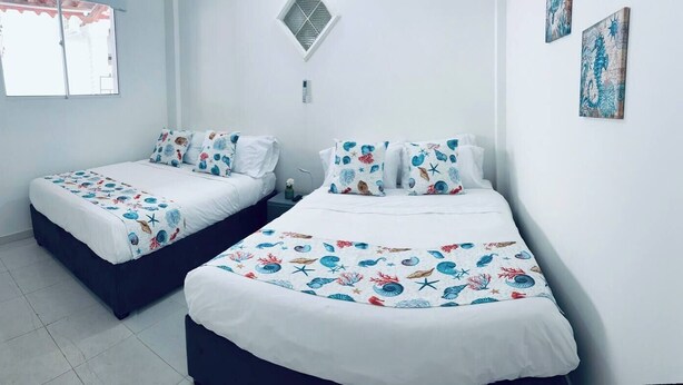 Two single beds with matching sea-themed bedding, a small window, and a wall-mounted air conditioning unit. - Turbay House 4 (Cartagena de Indias)