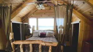 Una cama de madera rústica con dosel en una habitación estilo cabaña.