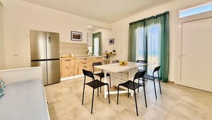 A modern kitchen with a refrigerator, dining table, and chairs. - Sea Life Giulia, 200 meters from the beach (ALCAMO)