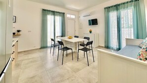 A modern, well-lit room with a dining table, chairs, a bed, and a TV mounted on the wall. - Sea Life Giulia, 200 meters from the beach (ALCAMO)