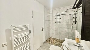 A modern bathroom with a shower, a white radiator, a sink, and a mirror. - Charming 3 bedrooms with a cozy terrace (Walferdange)