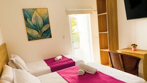 Habitación de hotel con dos camas, un escritorio, una silla, un cuadro y un televisor.