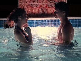 Dos personas en un jacuzzi con una pared de azulejos al fondo.