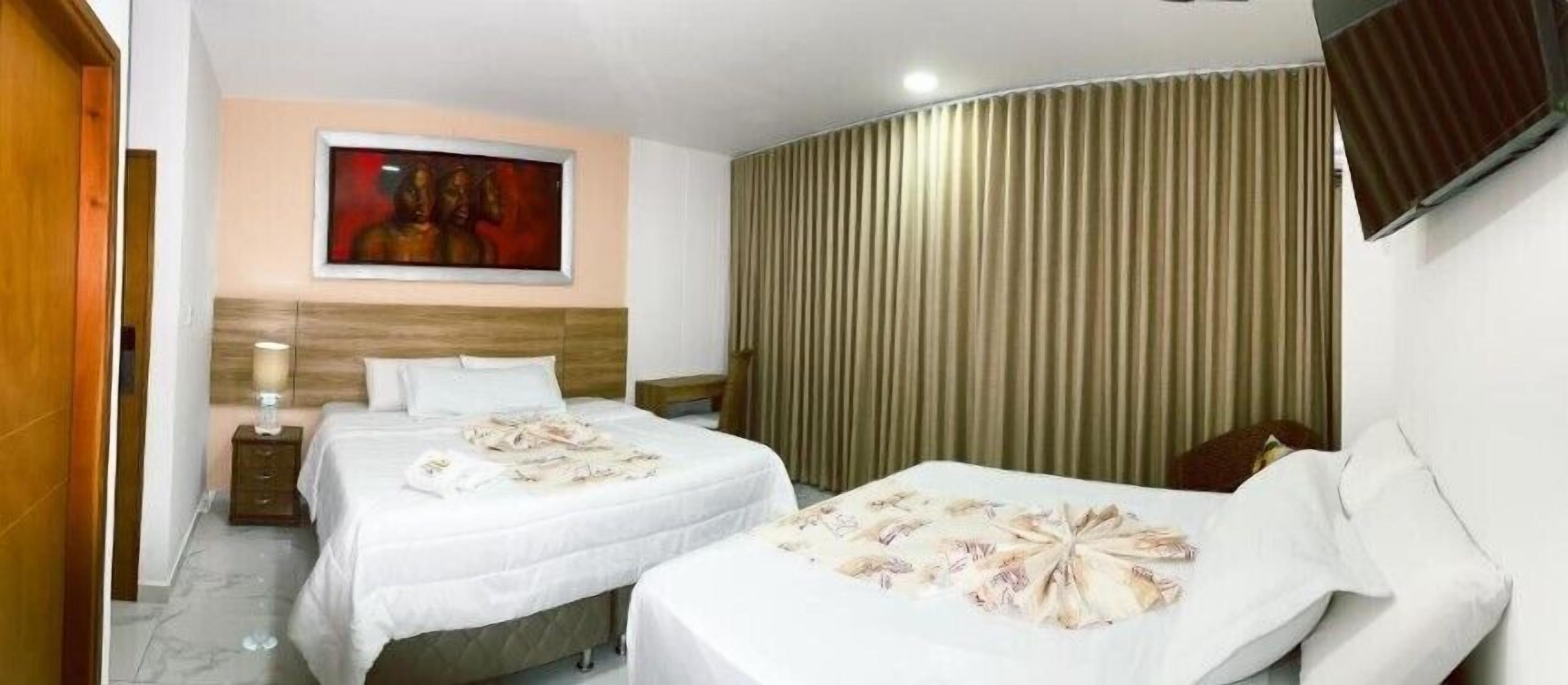 Habitación de hotel con dos camas, cabecero de madera, un cuadro en la pared y una cortina.