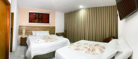 Habitación de hotel con dos camas, cabecero de madera, un cuadro en la pared y una cortina.