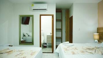 Une chambre d’hôtel avec deux lits, un grand miroir, un climatiseur, une armoire et une lampe de chevet.