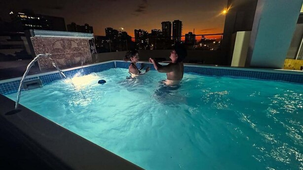 Una piscina con vista a un paisaje urbano al atardecer.