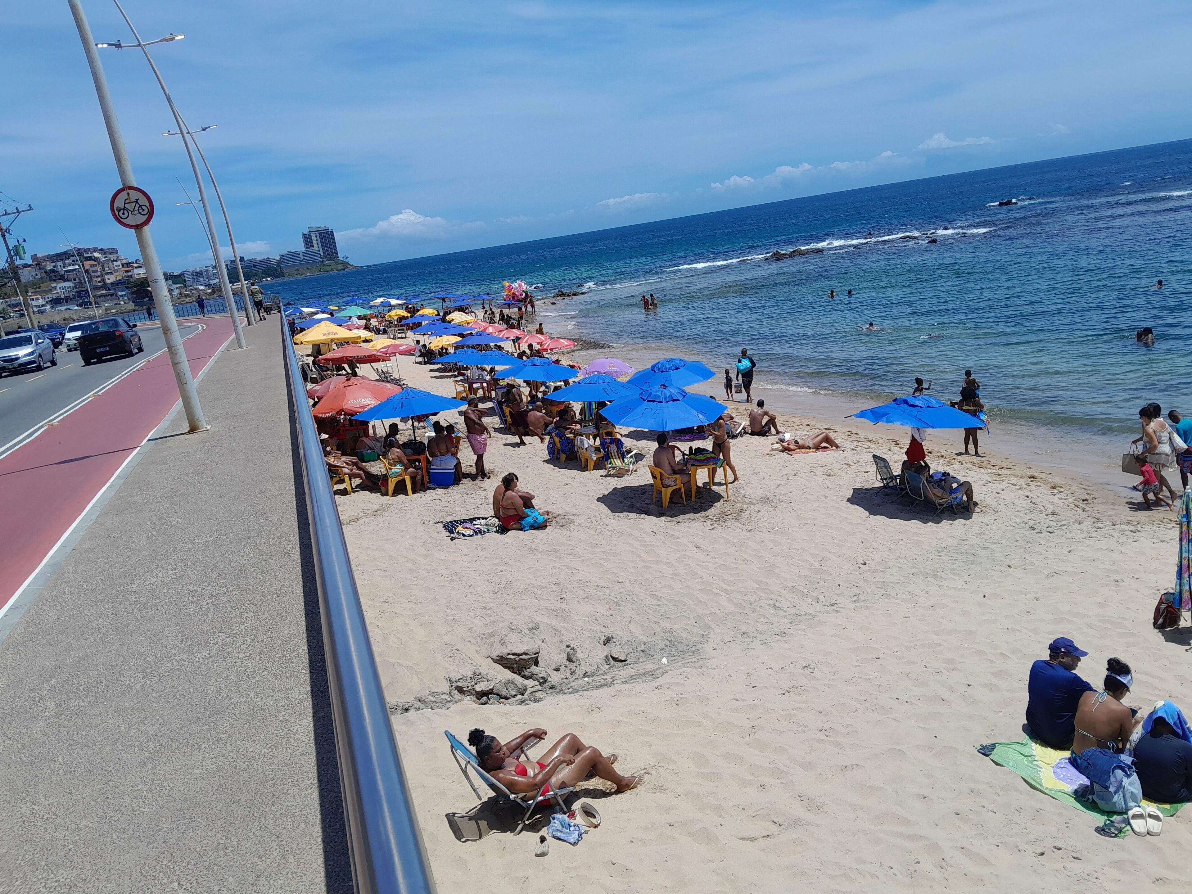 A beach with multiple umbrellas and people relaxing.