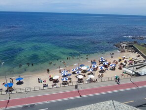 A beach with clear blue water, people sunbathing, and umbrellas. - DUPLEX PENTHOUSE WITH A POOL (Ondina Salvador)