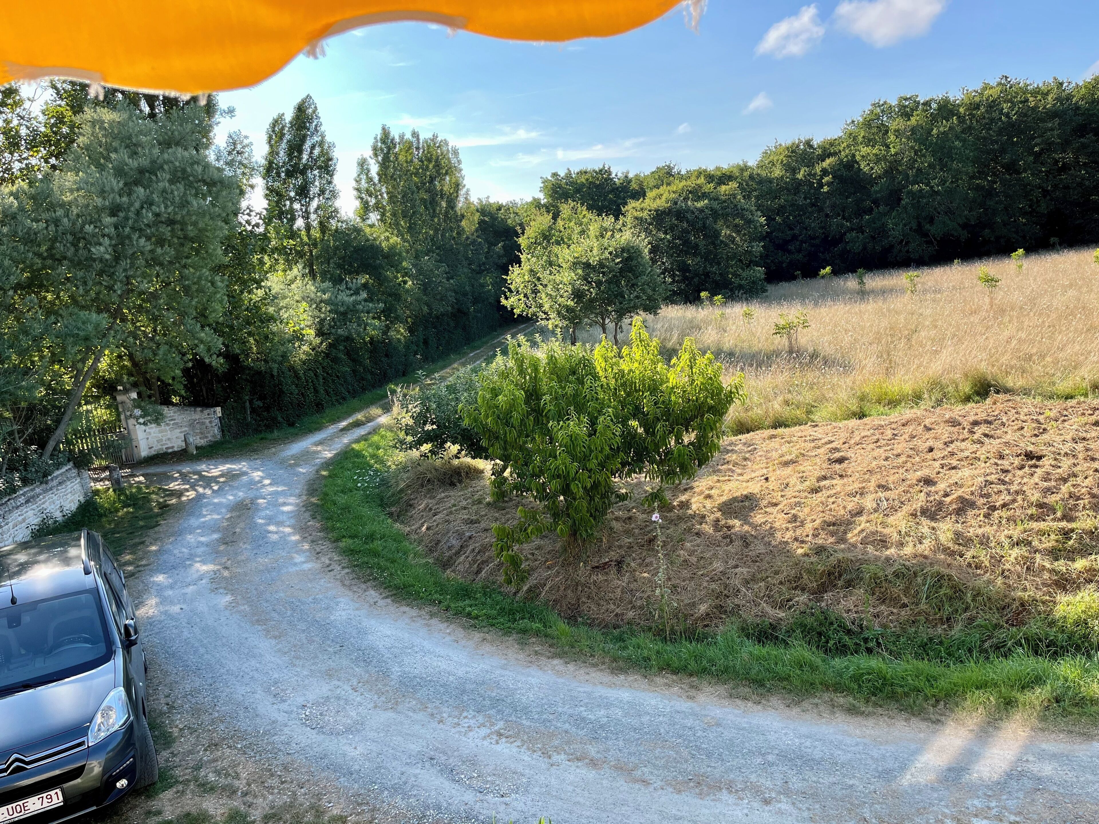 A rural road with a car parked on the side.