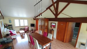 A spacious living area with a wooden dining table, chairs, a sofa, and a television. - Charming apartment in a 17th century farmhouse, sleeps 4 (LE CHATEAU DOLERON)
