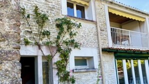A stone building with a balcony, a small window, and a white picket fence. - Charming apartment in a 17th century farmhouse, sleeps 4 (LE CHATEAU DOLERON)