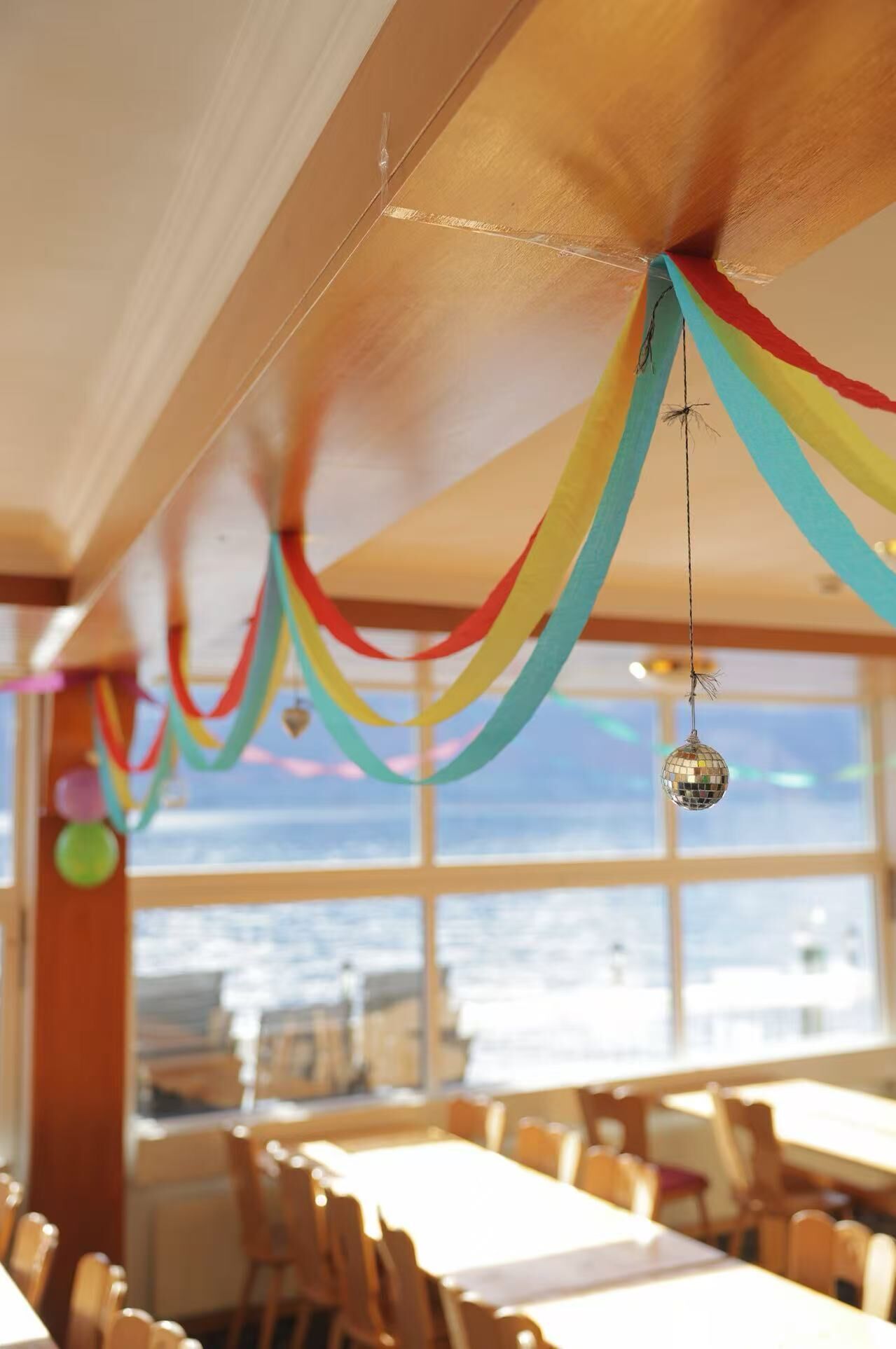 Un restaurant offrant une vue sur l’océan, décoré de guirlandes colorées et doté d’une boule à facettes.