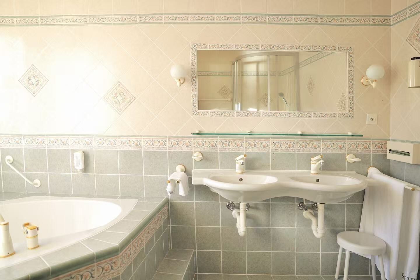 Un baño con dos lavamanos, una bañera grande y un box de ducha de vidrio.