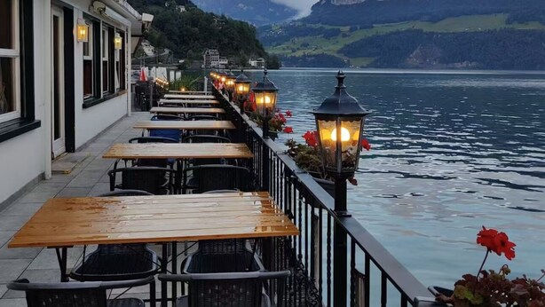 A lakeside restaurant with outdoor seating and a view of mountains. - Seehotel Schwert (Gersau)
