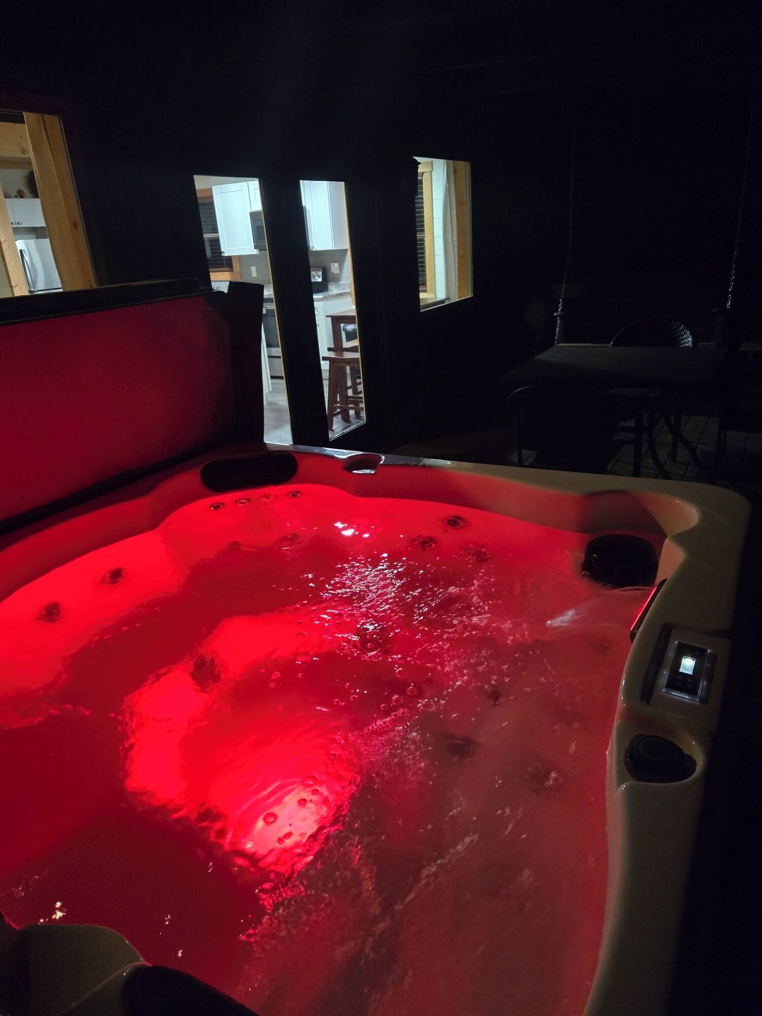 A hot tub with a red light, a wooden bench, and a view of the outside.