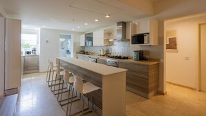 Una cucina moderna con isola centrale, sgabelli da bar, elettrodomestici in acciaio inossidabile e vista all'esterno.