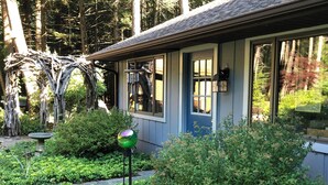 Ein Haus mit einer blauen Tür, einem Vogelbad und einem Garten mit verschiedenen Pflanzen.
