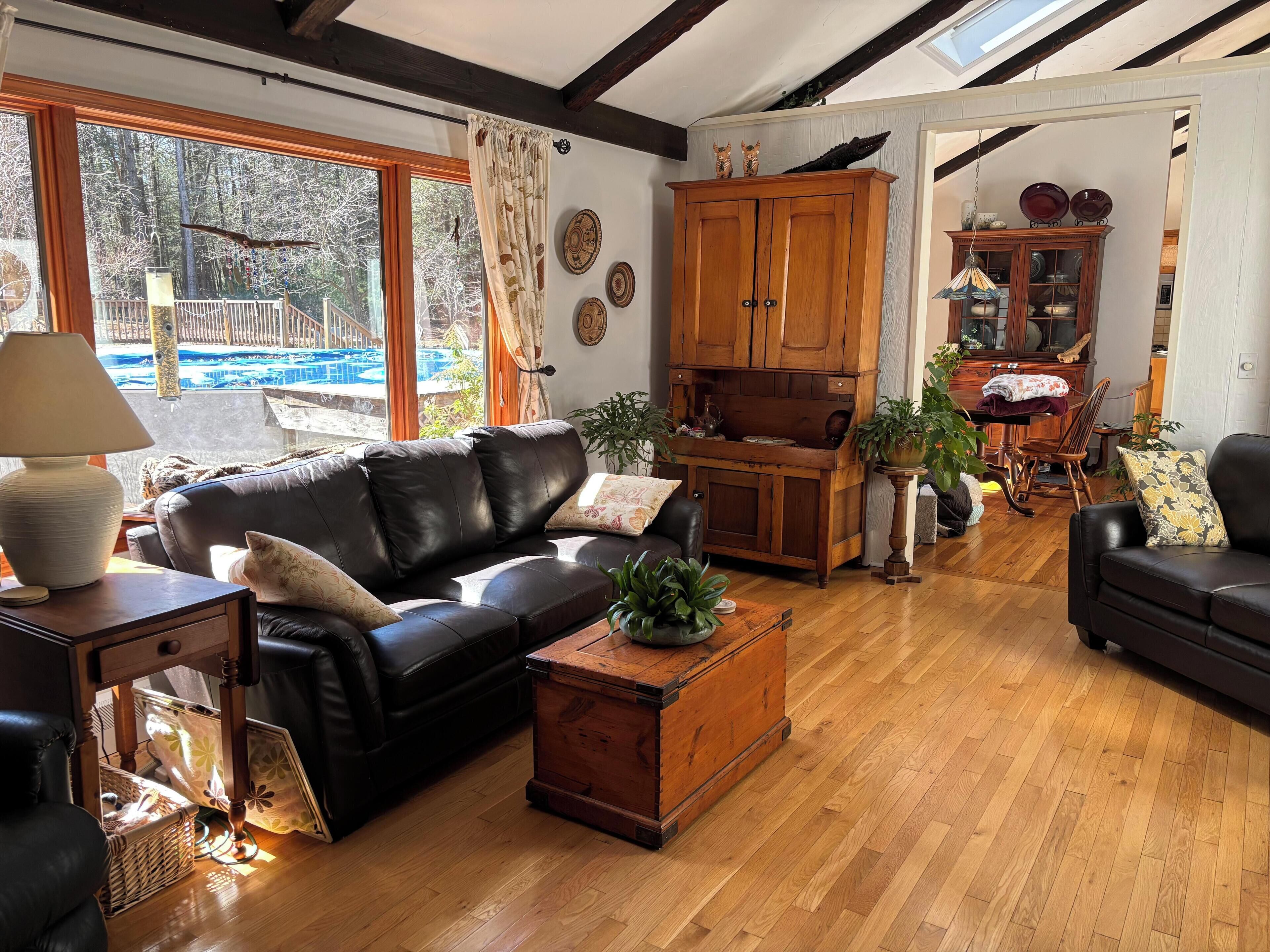 Un salon chaleureux avec un canapé en cuir, un meuble en bois et une vue sur une piscine.