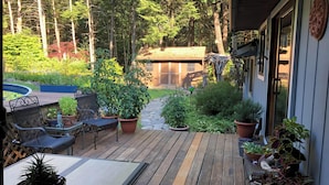 Eine Holzterrasse mit Gartenmöbeln, umgeben von Kübelpflanzen und einem Garten.
