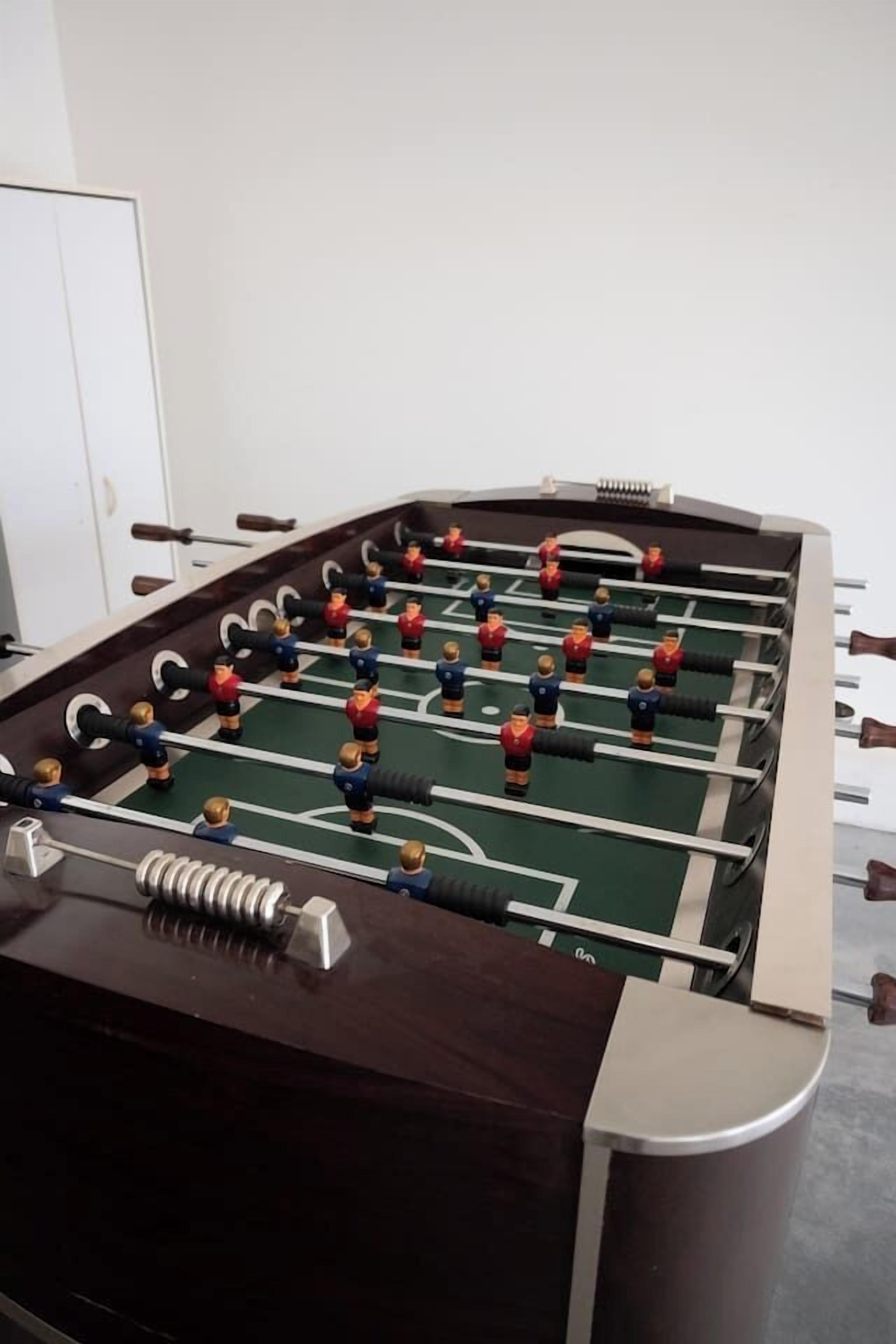 Un tavolo da calcio con base in legno scuro e superficie di gioco verde.
