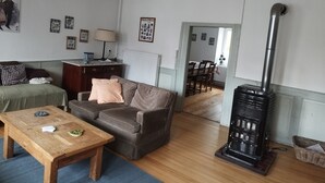 A cozy living room with a sofa, a wooden coffee table, a fireplace, and a dining area in the background. - La Bretz'elle, country house in the Vosges du Nord Natural Park (Lohr)