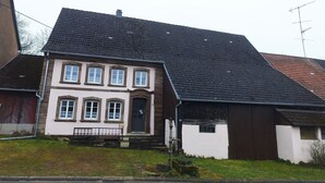 A two-story house with a steeply pitched roof, a front porch, and a small garden area. - La Bretz'elle, country house in the Vosges du Nord Natural Park (Lohr)