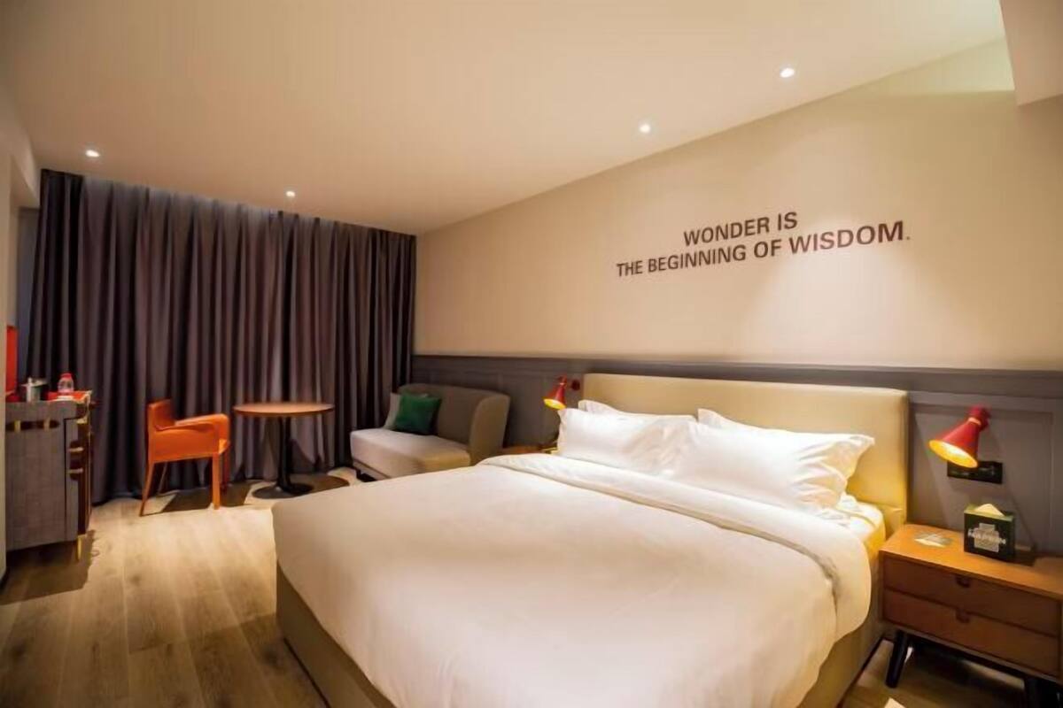 Ein modernes Hotelzimmer mit einem großen Bett, einem Schreibtisch, einem Sessel und einem kleinen Tisch.