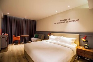A modern hotel room with a large bed, a desk, a chair, and a small table. - City Comfort Premier Hotel (Bozhou Weiwu Plaza) (Bozhou)