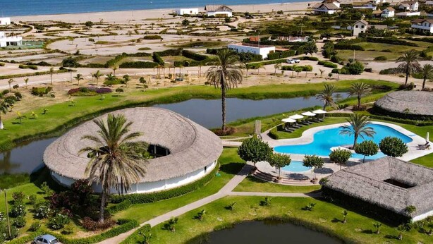 A resort with a large pool, palm trees, and a beach in the background. - HOP Munay Relajante en Campo y Playa en Chincha (El Carmen)