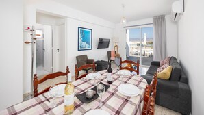 A dining area with a table set for four, a sofa, a television, and a view of a cityscape.