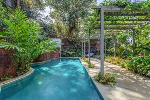 A pool surrounded by lush greenery and a pergola structure. - Stylish 2BR w Pool Near Candolim and Coco Beach (Verem)