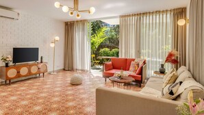 A modern living room with a flat-screen TV, a red sofa, a beige sofa, and a patterned floor. - Stylish 2BR w Pool Near Candolim and Coco Beach (Verem)