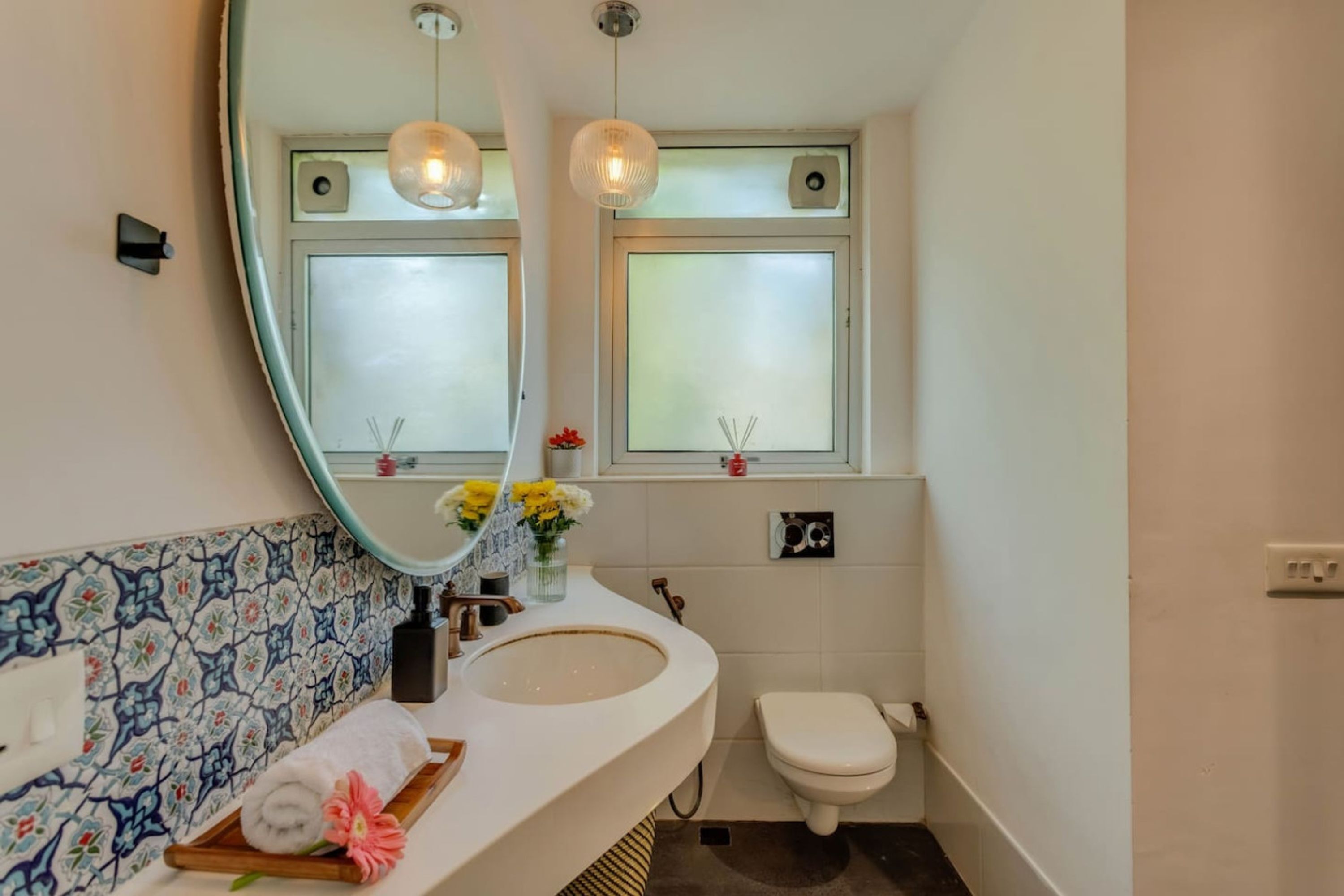 Ein Badezimmer mit einem weißen Waschbecken, einem Spiegel, einer Toilette und einem Fenster mit blickdichter Verglasung.