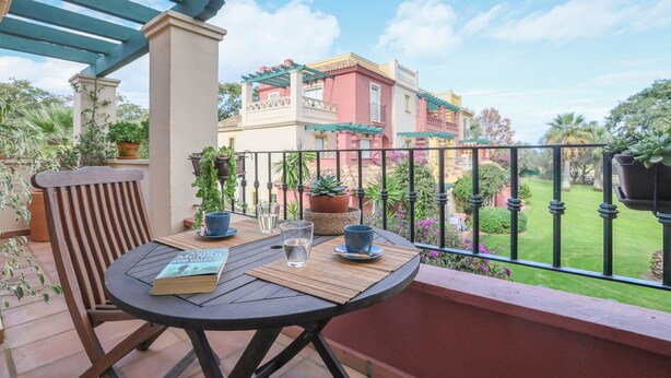 A balcony with a table, chairs, and a book. - Isla Canela Golf in Isla Canela (Ayamonte)