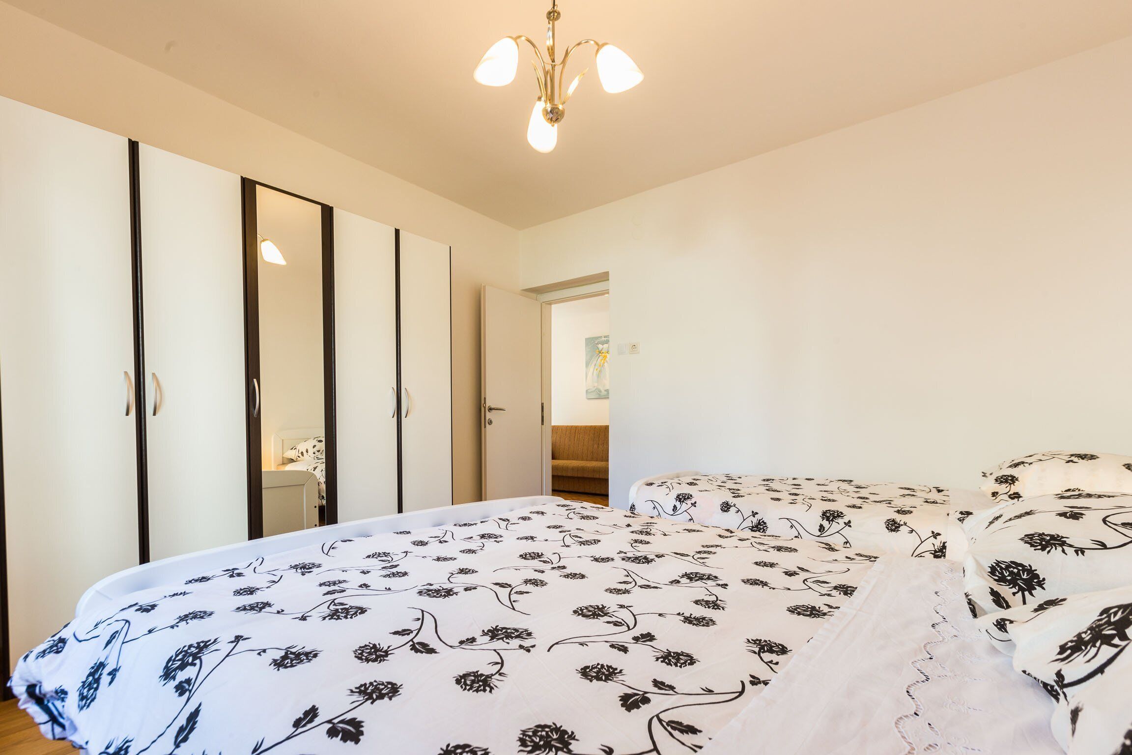 A bedroom with a bed, a wardrobe, and a mirror.