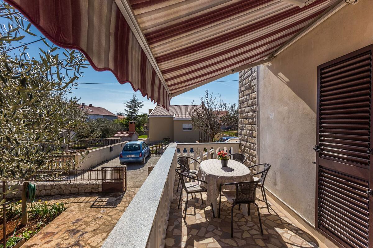 A patio with a table and chairs, a car parked outside, and a stone wall.