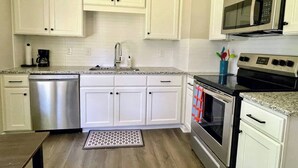 A modern kitchen with white cabinets, stainless steel appliances, and a granite countertop. - Ranch Home on Quiet Court Between Raleigh and Garner (Garner)