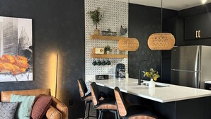 Una cocina moderna con una isla central, armarios negros e iluminación colgante.