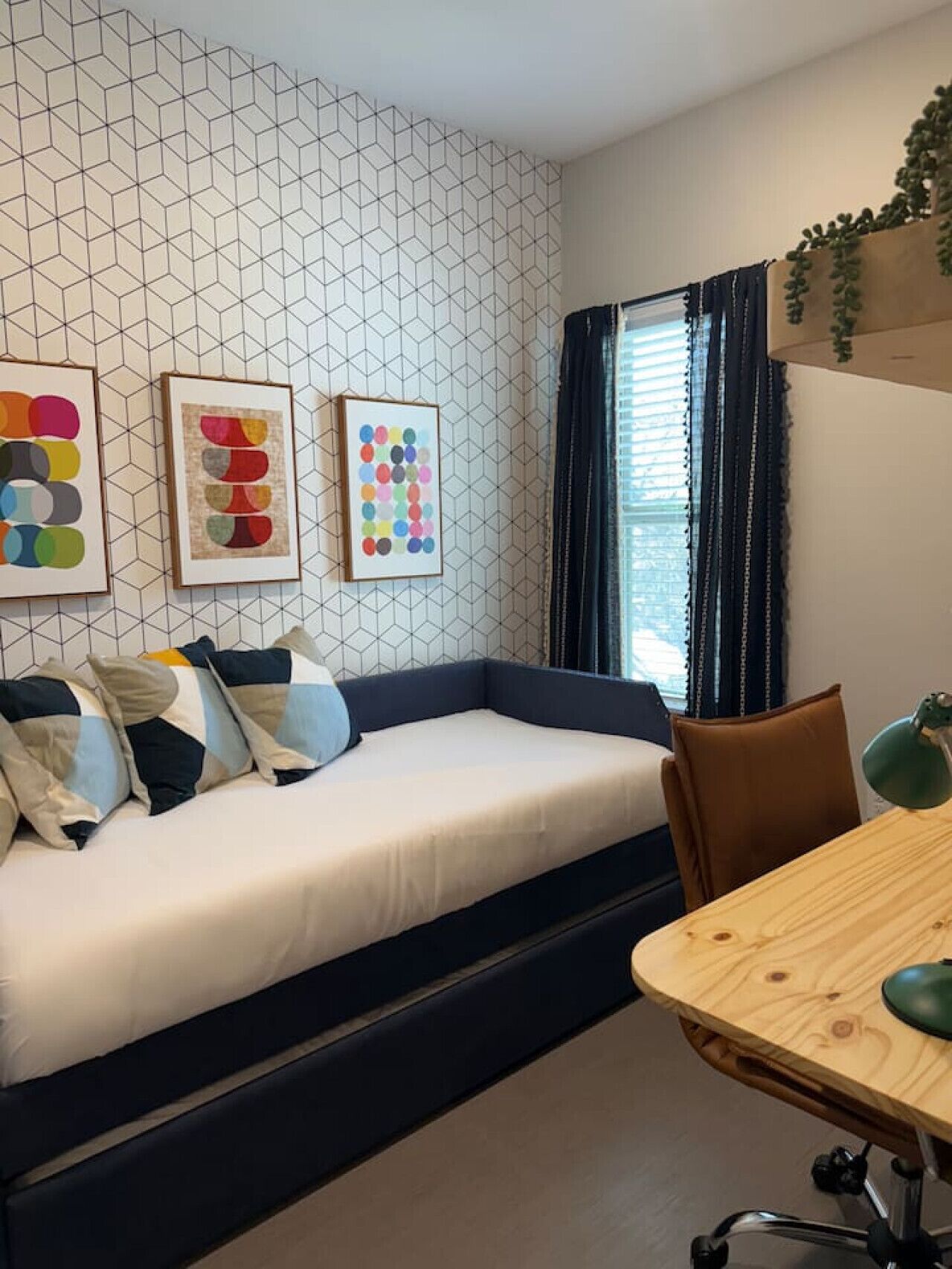 A modern room with a sofa bed, a wooden dining table, and artwork on the wall.