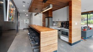 Una cocina moderna con una isla de madera, electrodomésticos de acero inoxidable y una zona de estar con un sofá gris.