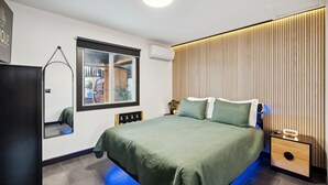 Un dormitorio moderno con cama, mesitas de noche, un espejo y una ventana.